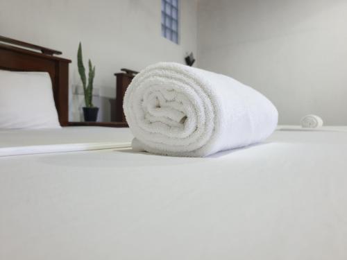 a roll of white towels sitting on a bed at Enara Luxury Stay in Katugastota