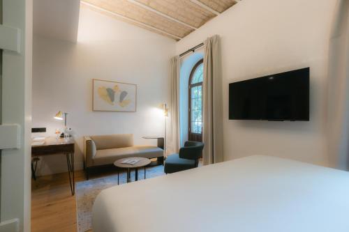 Habitación de hotel con cama, escritorio y TV. en Cavalta Boutique Hotel GL, en Sevilla