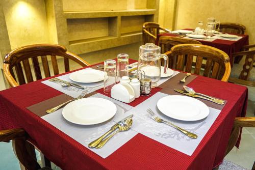 una mesa con platos y cubiertos de plata sobre un mantel rojo en Nexa Hotel en Arusha