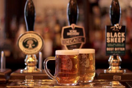 two glasses of beer sitting on a bar at White Hart Hotel & Apartments in Harrogate