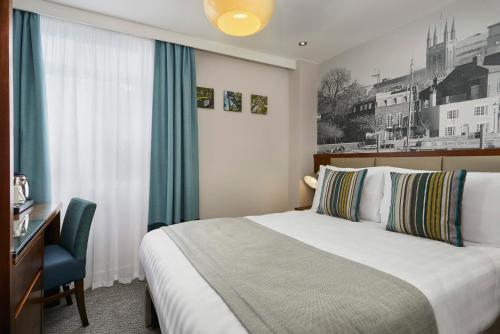 Seraphine Hammersmith Hotel في لندن: غرفه فندقيه بسرير ومكتب ونافذه