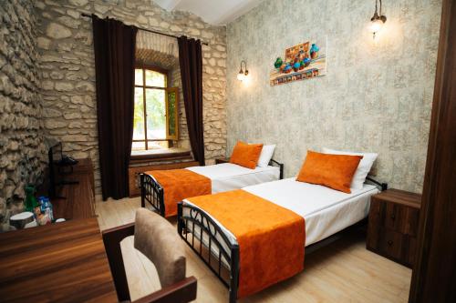 a bedroom with two beds and a stone wall at Art Hotel by ABAD Guest in Sheki