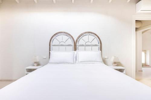 a bedroom with a white bed with two windows at VerdeOlivo 1876 - Apartments & Pool in Mezzane di Sotto