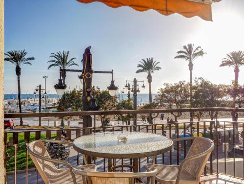 una mesa y sillas en un balcón con palmeras en Soleil by Hello Homes Sitges, en Sitges