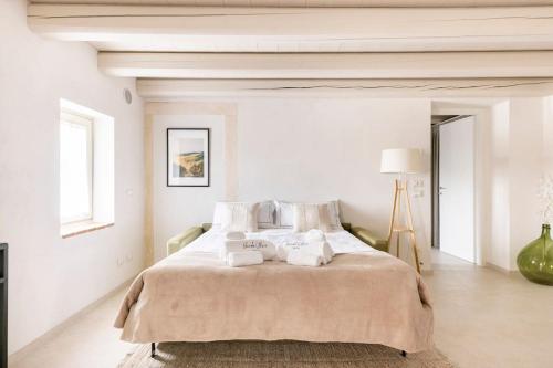 a white bedroom with a large bed with towels on it at VerdeOlivo 1876 - Apartments & Pool in Mezzane di Sotto