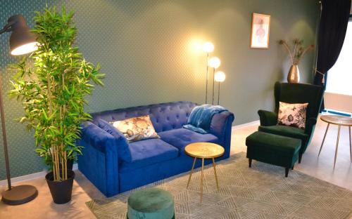 a living room with a blue couch and a chair at The Flowerhouse in Zandvoort