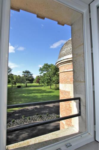 a window with a view of a field and a building at Manoir de Montigny in Russy-Bémont