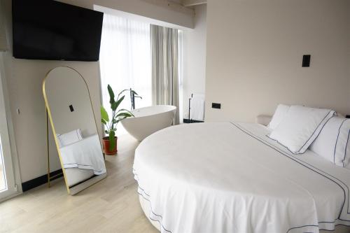 a white bedroom with a large bed and a mirror at Hotel Neguetxea in Guernica y Luno