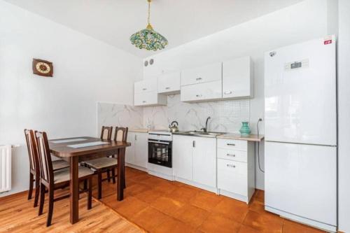 a kitchen with white cabinets and a table and chairs at Urbannest_Łąkowa in Gdańsk