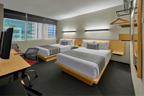 a room with two beds and a desk and a computer at City Express Plus by Marriott Monterrey Nuevo Sur in Monterrey