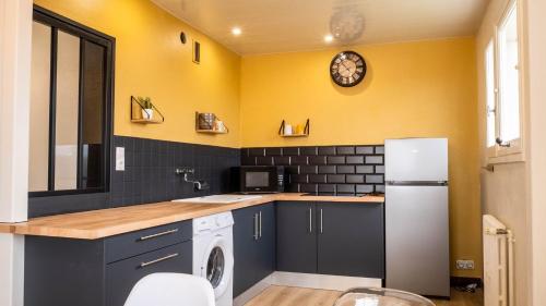 Kuchnia z czarnymi i żółtymi ścianami i lodówką w obiekcie Le Montbernage - Beautiful modern apartment w mieście Poitiers