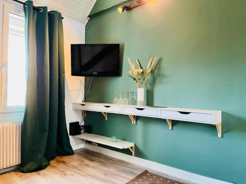 ein Wohnzimmer mit einem TV an einer grünen Wand in der Unterkunft Joli appartement en duplex, parking privé Hortillonage in Amiens