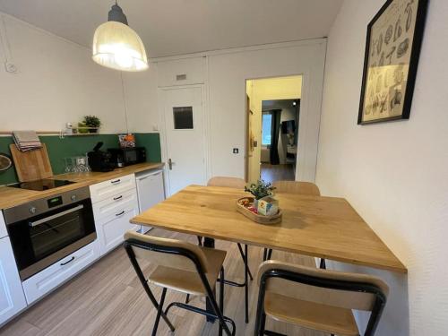 Il comprend une cuisine avec une table et des chaises en bois. dans l'établissement Joli appartement en duplex, parking privé Hortillonage, à Amiens