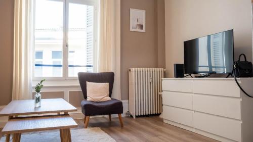 ein Wohnzimmer mit einem TV auf einer Kommode und einem Stuhl in der Unterkunft L'hôtel de ville - Joli petit T2 en centre-ville in Poitiers