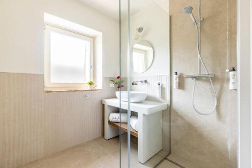 a white bathroom with a sink and a shower at VerdeOlivo 1876 - Apartments & Pool in Mezzane di Sotto