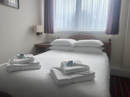 a bedroom with two beds with towels and a window at Brig Inn Hotel in Aberdeen