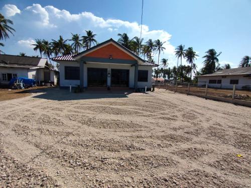 a house on a dirt road with palm trees at Tok Mek Homestay in Setiu