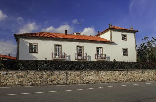 a white building with a red roof on a stone wall at Hotel Rural Quinta de Sao Sebastiao in Barroselas