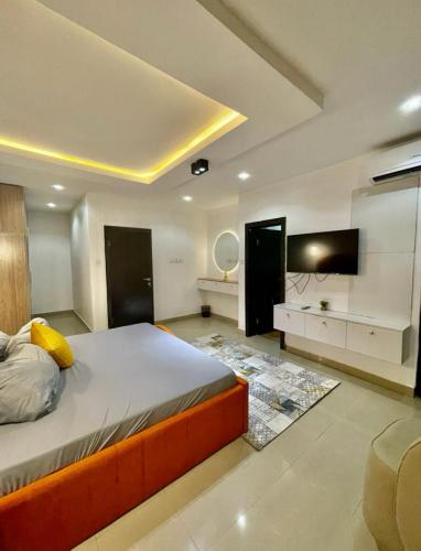 a bedroom with a bed and a flat screen tv at AL_MUBARAK ,APARTMENT in Ikeja