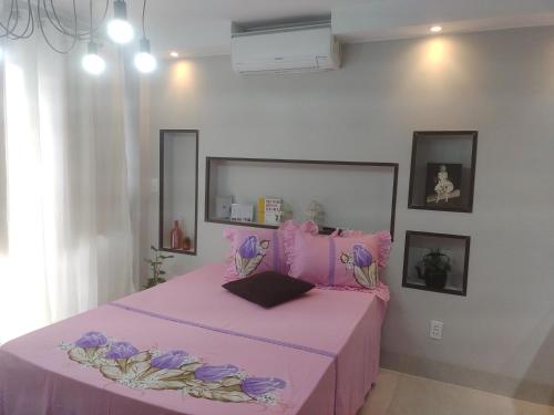 a pink bed with purple sheets in a room at Apto 115 N B a 6 km do aeroporto in Núcleo Bandeirante
