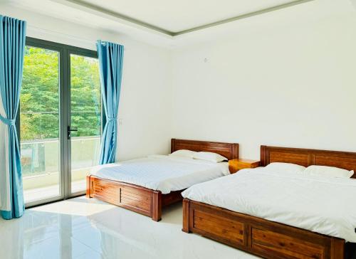 2 camas en una habitación con ventana en Lava Rock Viet Nam Lodge, en Cát Tiên