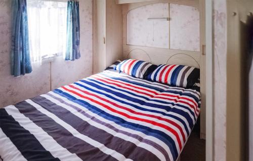 a bed with a striped blanket on it in a room at Lovely Home In Mielno With Kitchen in Mielno