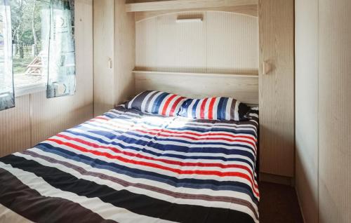 a bed in a small room with a striped blanket at 2 Bedroom Amazing Home In Mielno in Mielno