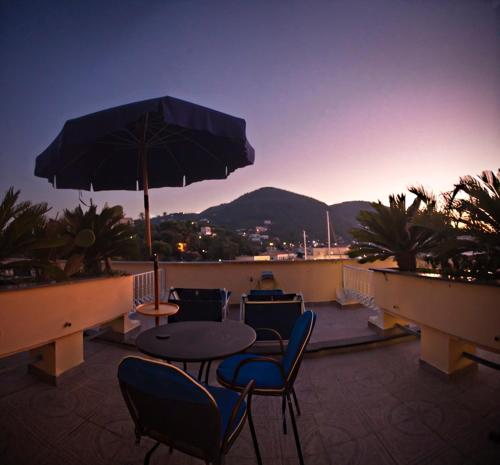 a patio with a table and chairs and an umbrella at Aragona Palace Hotel & Spa in Ischia