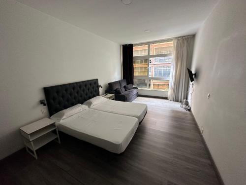 a bedroom with a bed and a couch and a window at AP DEUSTO in Bilbao