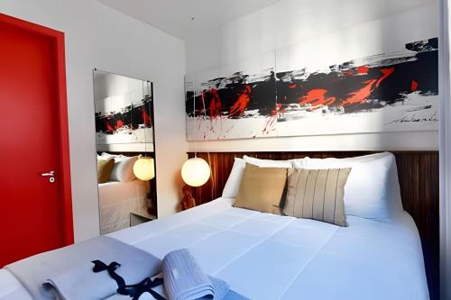 1 dormitorio con cama blanca y puerta roja en Exclusivo na Liberdade com Piscina e Wi-fi 300mb, en São Paulo
