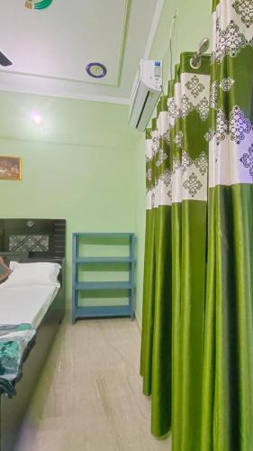Habitación con cama y cortina verde en Prakash Homestay en Ayodhya
