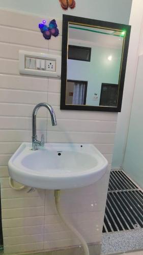 lavabo blanco en el baño con espejo en Prakash Homestay en Ayodhya