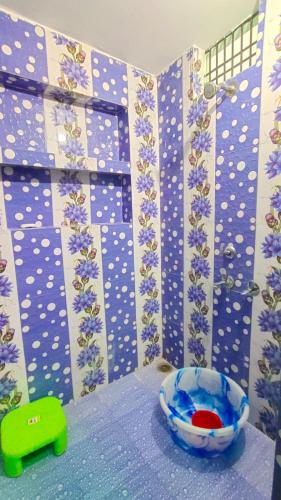 un baño con una pared azul y blanca con flores púrpuras en Prakash Homestay en Ayodhya