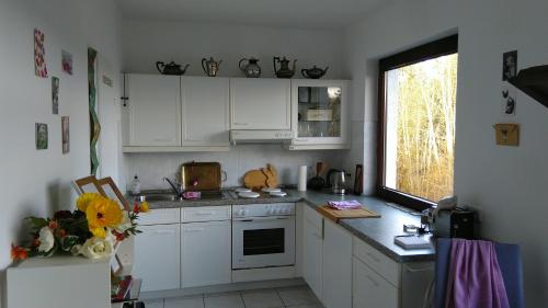 uma cozinha com armários brancos e uma janela em Zimmer mit Aussicht em Schulenberg im Oberharz