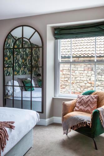 a bedroom with a mirror and a chair and a bed at The Prince of Waterloo - Boutique Guest Rooms in Winford