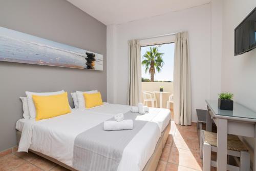 1 dormitorio con 1 cama blanca grande con almohadas amarillas en Cavo Doro en Kalamaki