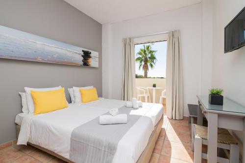 a bedroom with a large white bed with yellow pillows at Cavo D'oro All Inclusive Resort in Kalamaki
