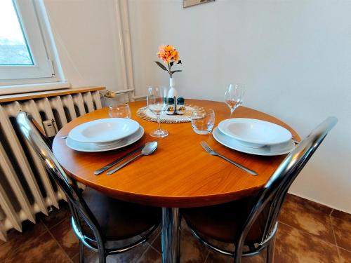 - une table en bois avec des assiettes et des verres à vin dans l'établissement Apartmán Green, à Nitra