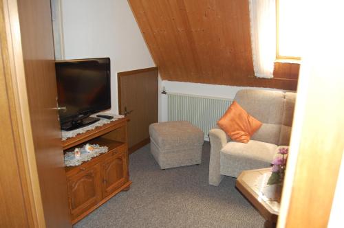 ein Wohnzimmer mit einem TV und einem Stuhl in der Unterkunft Haus Resi in Wiesmoor