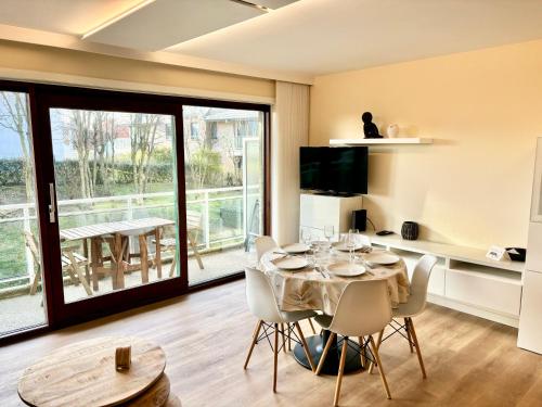 een eetkamer met een tafel en stoelen en een balkon bij Peppino 0101 in Koksijde