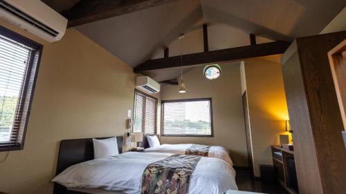um quarto com uma cama e duas janelas em ほたるの長屋 em Yamaga