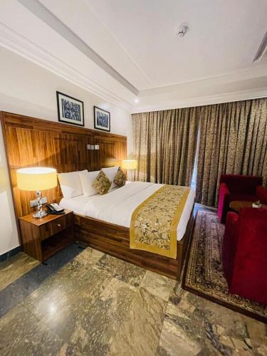 a hotel room with a bed and a chair at Qualibest Grand Hotels in Abuja