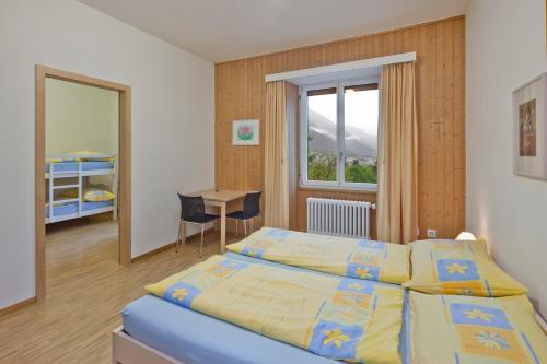1 dormitorio con 2 camas, mesa y ventana en Hotel Haus Schönstatt contactless-Check-In, en Brig