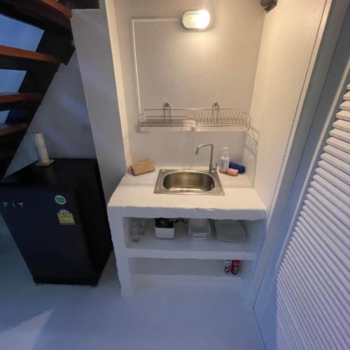 a sink in a small bathroom with a staircase at Acqualanta House in Ko Lanta