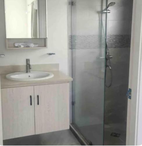 a bathroom with a sink and a shower with a mirror at Remarkable 2-Bed House in Discovery Bay in Discovery Bay