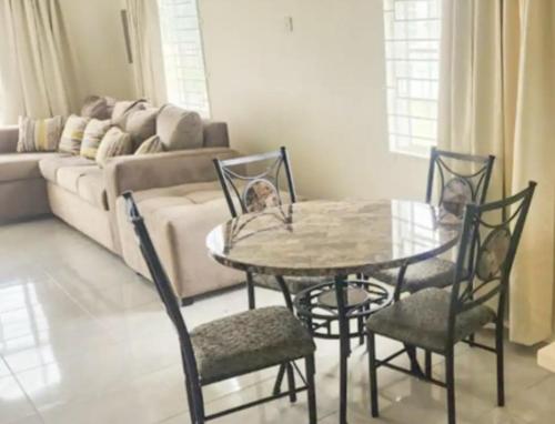 a table and chairs in a living room with a couch at Remarkable 2-Bed House in Discovery Bay in Discovery Bay