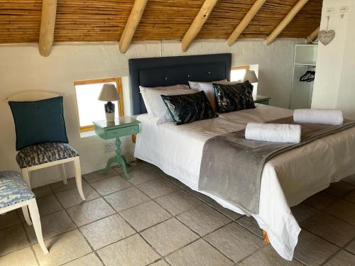 a bedroom with a large bed and a chair at Nova Vida in Paternoster