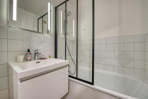 ein weißes Bad mit einem Waschbecken und einer Dusche in der Unterkunft La Perle de Houlgate Élégance & Vue 4 pers in Houlgate