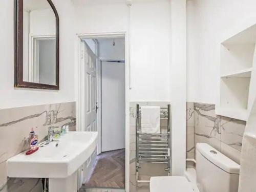 a bathroom with a sink and a toilet and a mirror at Pass the Keys Spacious Apartment in Honor Oak in London