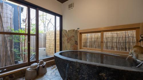 a bathroom with a large tub in a room with windows at ほたるの長屋 in Yamaga